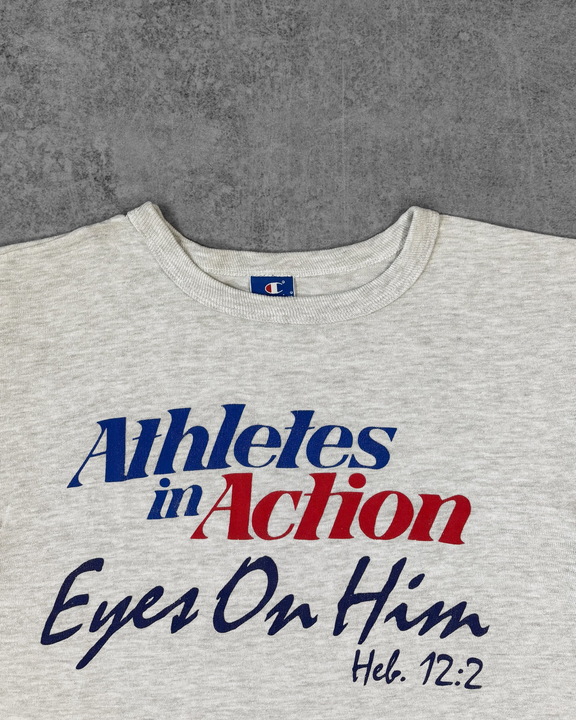 Print detail of the 'Athletes in Action - Eyes On Him - Heb. 12:2' graphic on the Champion t-shirt