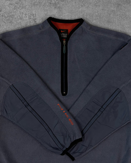 Detail of the embroidered orange Nike Swoosh logo on the lower back of the pullover
