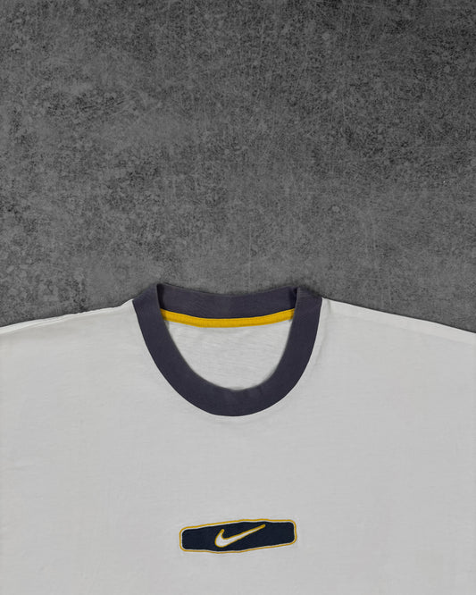 Detail of the embroidered Nike Swoosh patch on the chest in navy and yellow